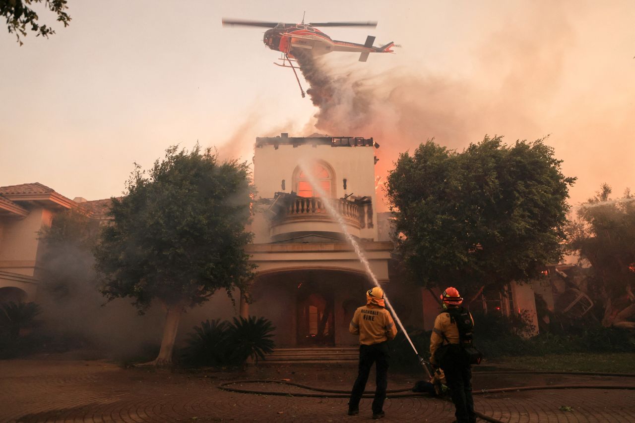 Firefighters work to extinguish a fire while a helicopter drops retardant in Camarillo, California on November 6.