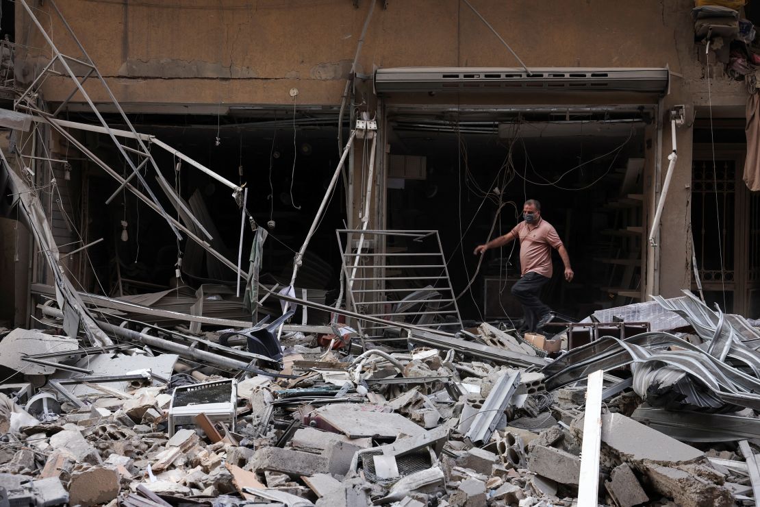 A man walks on rubble near damaged buildings, in the aftermath of Israeli strikes on Beirut's southern suburbs, during a Hezbollah media tour on November 9, 2024.