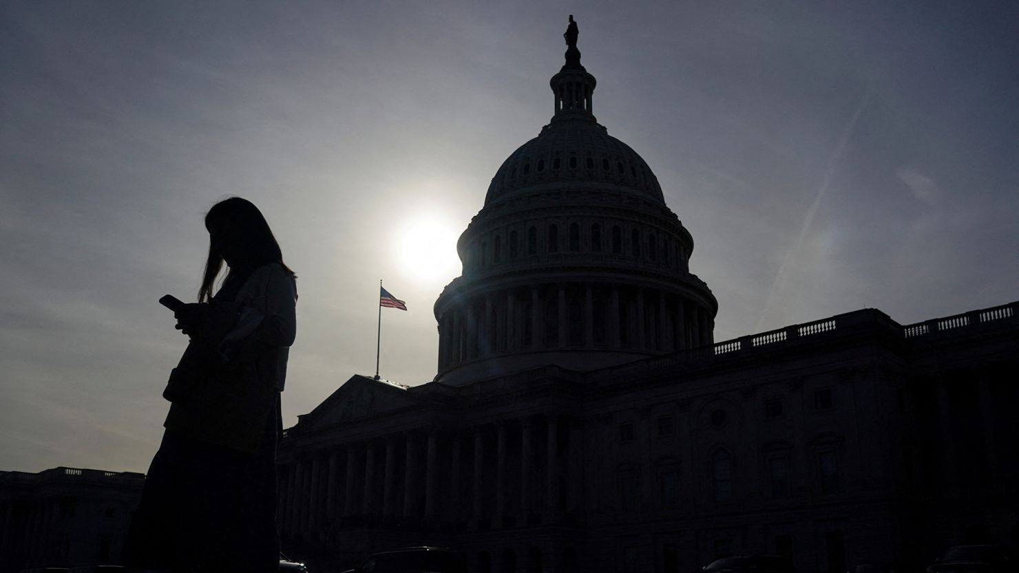 A person uses a mobile phone with the US Capitol building in the background on November 13, 2024.