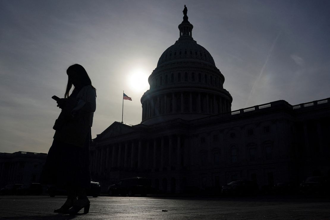 A person uses a mobile phone with the US Capitol building in Washington on November 13, 2024.