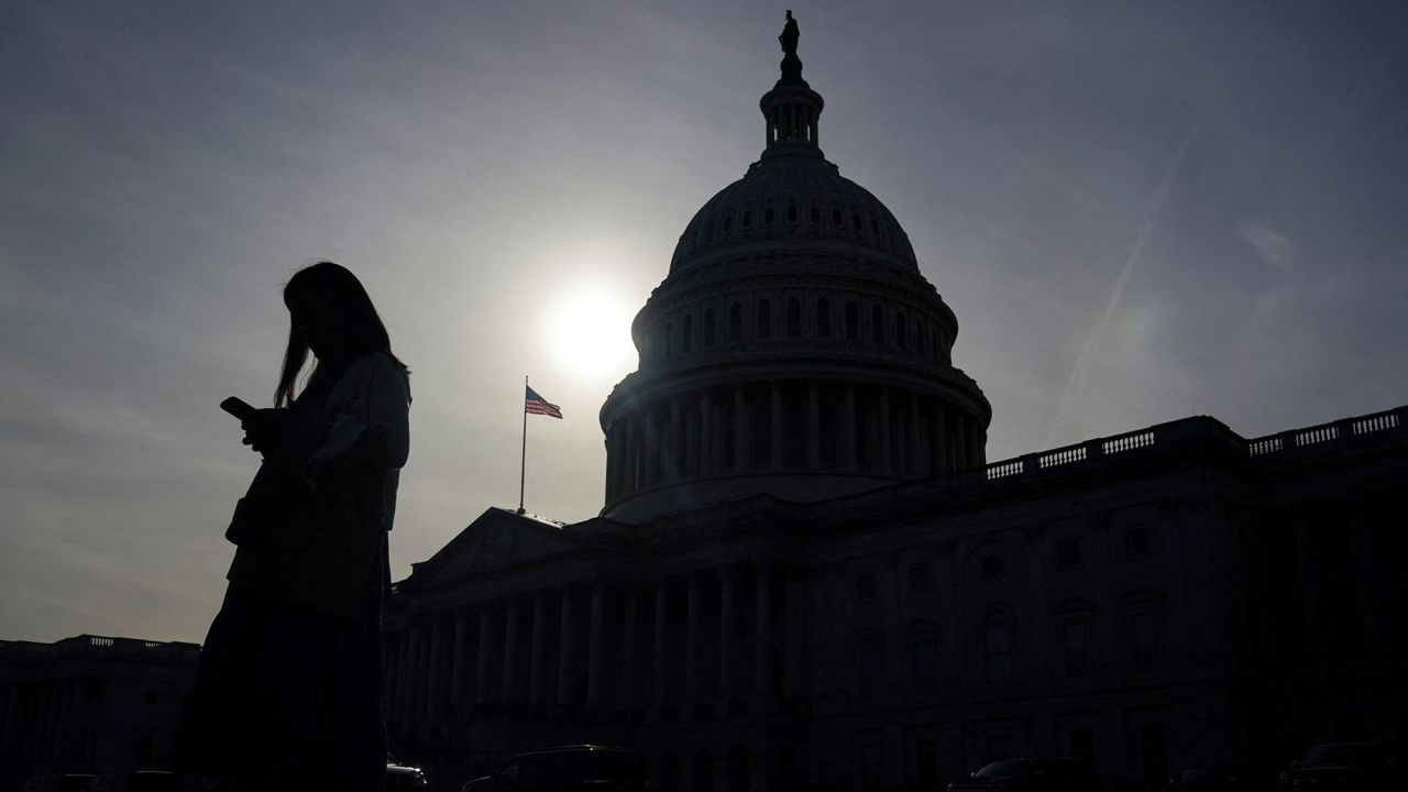 A person uses a mobile phone with the U.S. Capitol building in the background on November 13, 2024.
