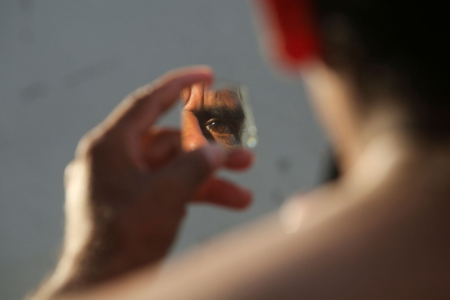 A migrant looks in a mirror as he shaves at the entrance to Icacos beach, during a pause on his journey to the northern border, in Acapulco, Mexico, November 27, 2024. REUTERS/Javier Verdin