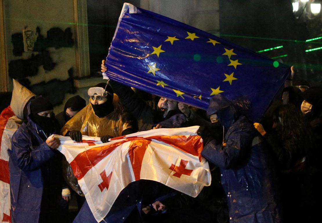 Demonstrators react as law enforcement officers use a water cannon during a protest against the new government's decision to suspend the European Union accession talks and refuse budgetary grants until 2028, in Tbilisi, Georgia, on December 1, 2024.