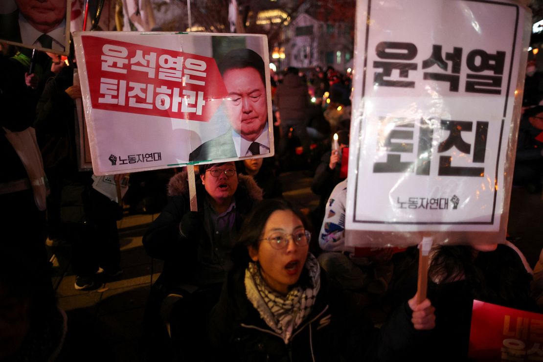 People hold signs during a candlelight vigil to condemn South Korean President Yoon Suk Yeol's declaration of the martial law, which was reversed hours later, and to call for his resignation, at the national assembly in Seoul on December 4, 2024.