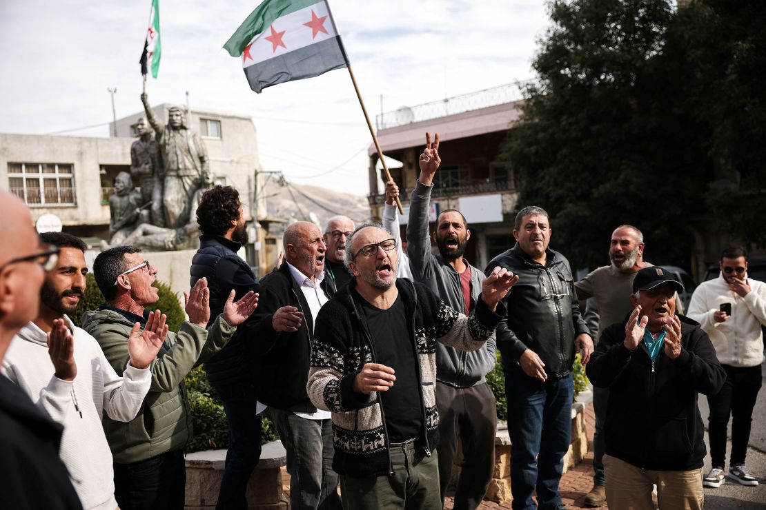 A person holds up a Syrian opposition flag in a Druze village in the Israeli-occupied Golan Heights, on December 8, 2024, as men celebrate the fall of Assad's regime.