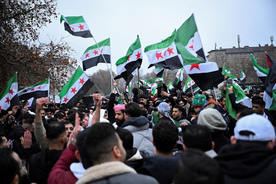 People wave Syrian opposition flags, as they gather at Oranienplatz square, after Syrian rebels announced that they have ousted Syria's Bashar al-Assad, in Berlin, Germany December 8, 2024. REUTERS/Annegret Hilse REFILE - CORRECTING FROM "SYRIAN FLAGS" TO "SYRIAN OPPOSITION FLAGS".