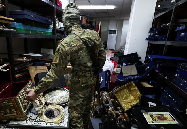 A rebel fighter rummages through personal souvenirs belonging to deposed president Bashar al-Assad at one of the rooms in the Presidential Palace in Damascus on December 10.