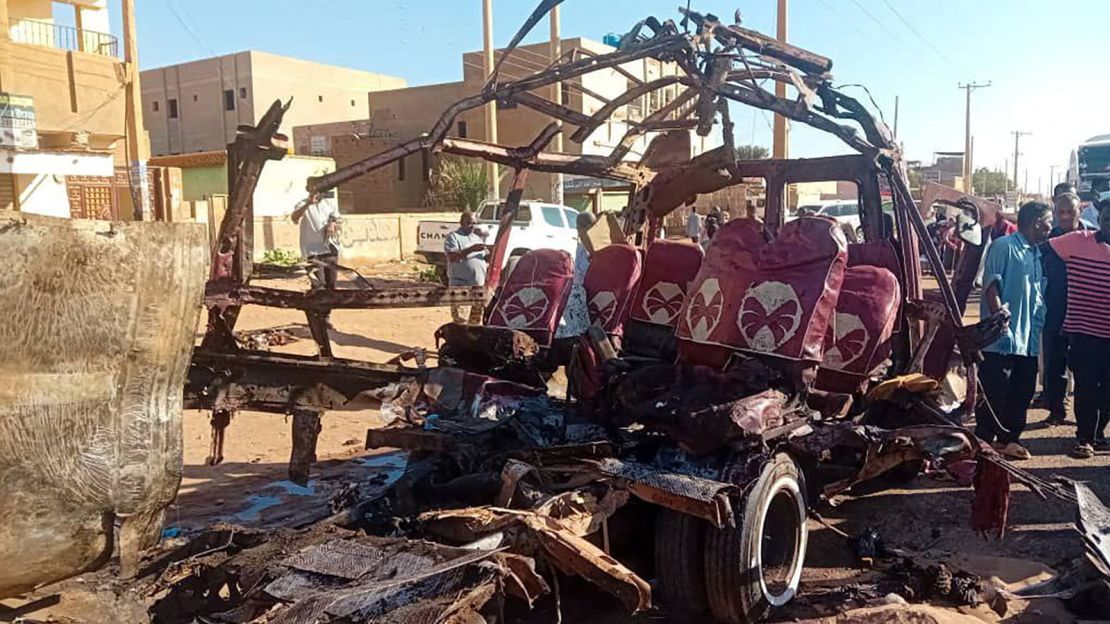 People gather near a destroyed vehicle, following shelling in Omdurman, Sudan on December 10, 2024.