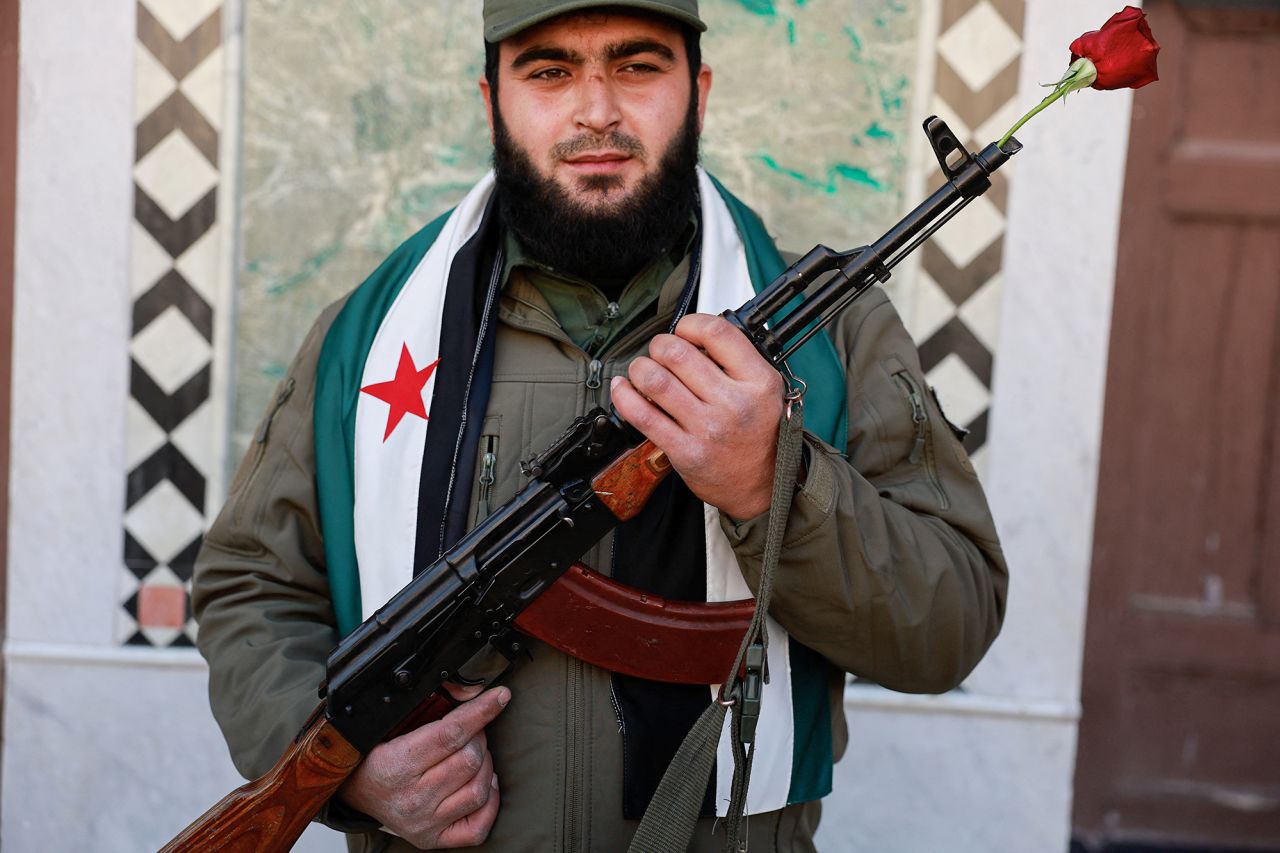 A fighter of the ruling Syrian body stands with a weapon and a flower, at Umayyad Mosque, Damascus, on December 13.