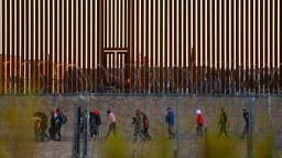 Migrants seeking asylum in the United States gather near the border wall after crossing a razor wire fence deployed to inhibit their crossing into the United States, as a member of the Texas National Guard escorts them, as seen from Ciudad Juarez, Mexico December 19, 2024.