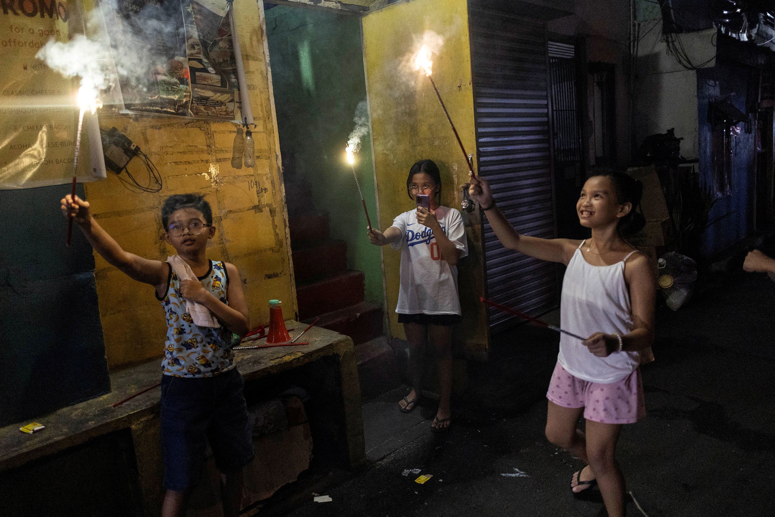 Children light firecrackers on a street in Mandaluyong, Philippines.