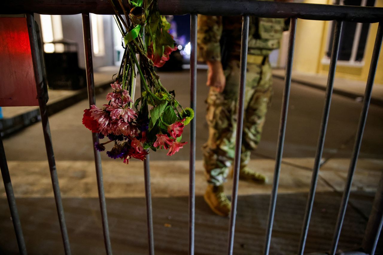 A military personnel stands near flowers on a fence near the scene where a vehicle drove into a crowd during New Year's celebrations in New Orleans on January 1.