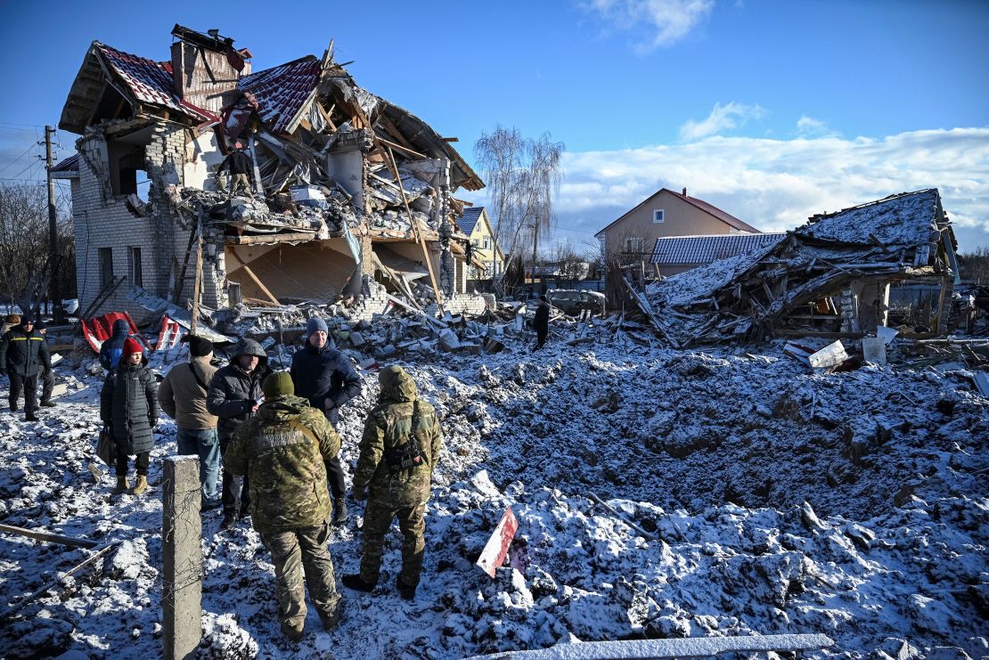 Residents and bomb squad members stand in front of a house destroyed by a Russian missile strike on Saturday.