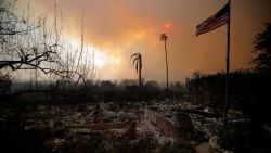 Una bandera estadounidense ondea sobre los restos de casas destruidas mientras los fuertes vientos alimentan los devastadores incendios forestales en el área de Los Ángeles, obligando a la gente a evacuar, en el barrio de Pacific Palisades, en el oeste de Los Ángeles.