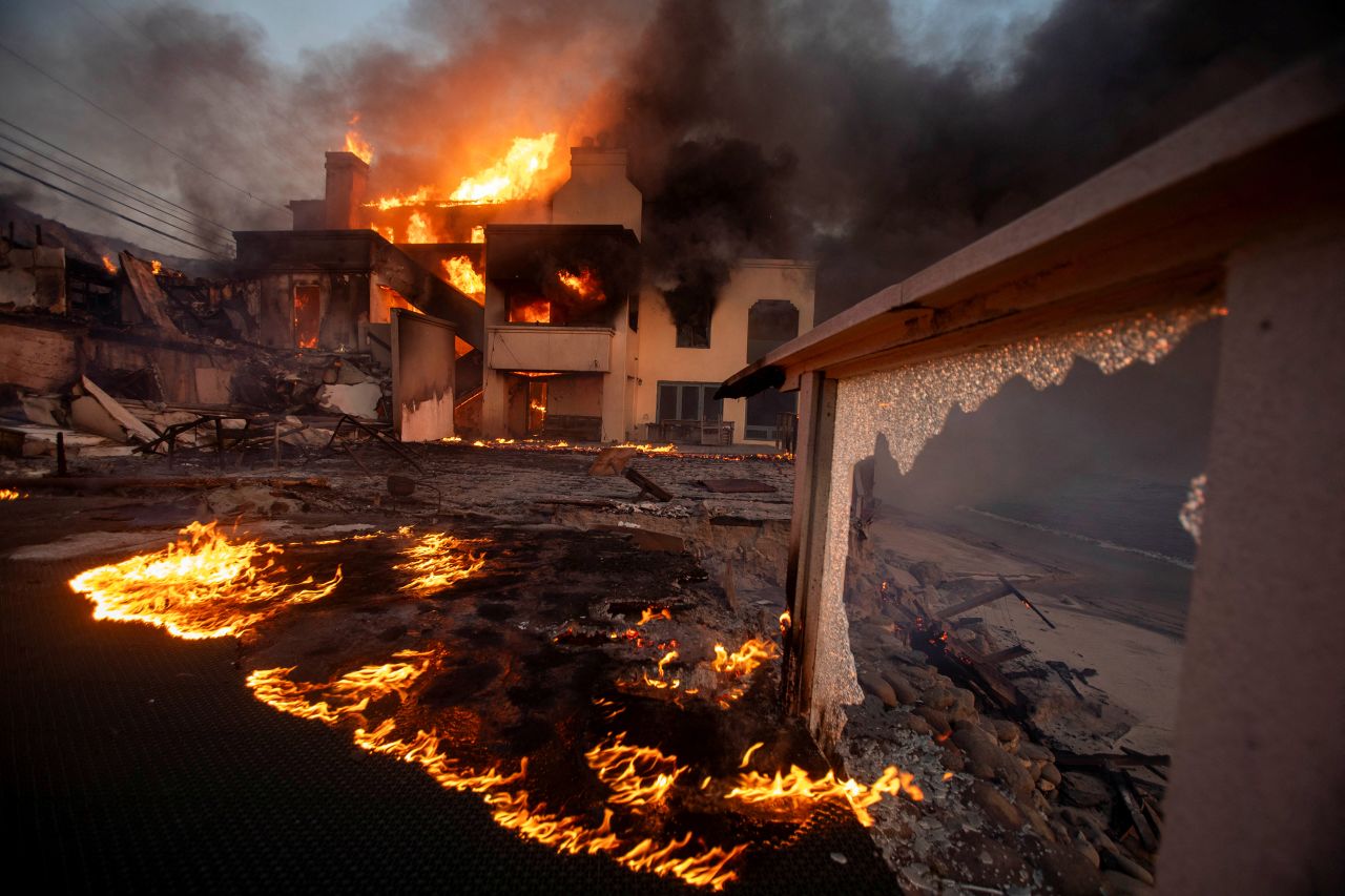 Flames and smoke rise from structures as the Palisades fire burns during a windstorm on the west side of Los Angeles, on January 8.