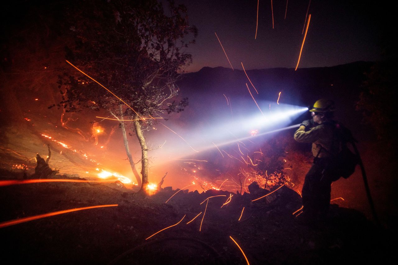 The wind whips embers while a firefighter battles flames in the Angeles National Forest in Altadena, California, on January 9.