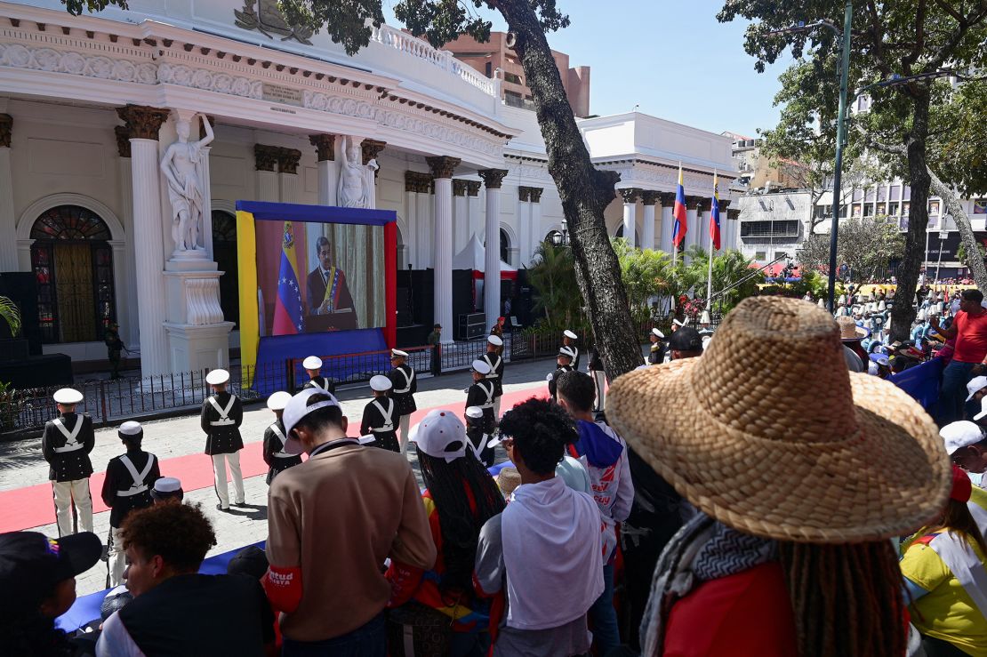 People watch a screen as ⁢VenezuelaS President Nicolas Maduro​ is sworn in for a third six-year ‍term, in Caracas, Venezuela, on January 10.