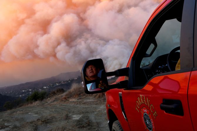 Alec Miller from the Torrance Fire Department looks at smoke billowing from the Palisades Fire in the Brentwood area of Los Angeles.