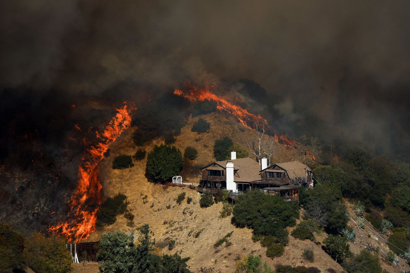 The Palisades Fire burns near a house in Mandeville Canyon.