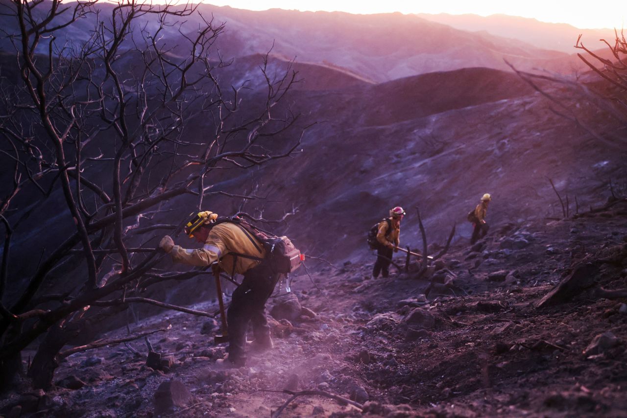 Members of a CalFire crew mop up hotspots from the burn scar of the Palisades Fire near Mulholland Drive in Los Angeles on Wednesday.