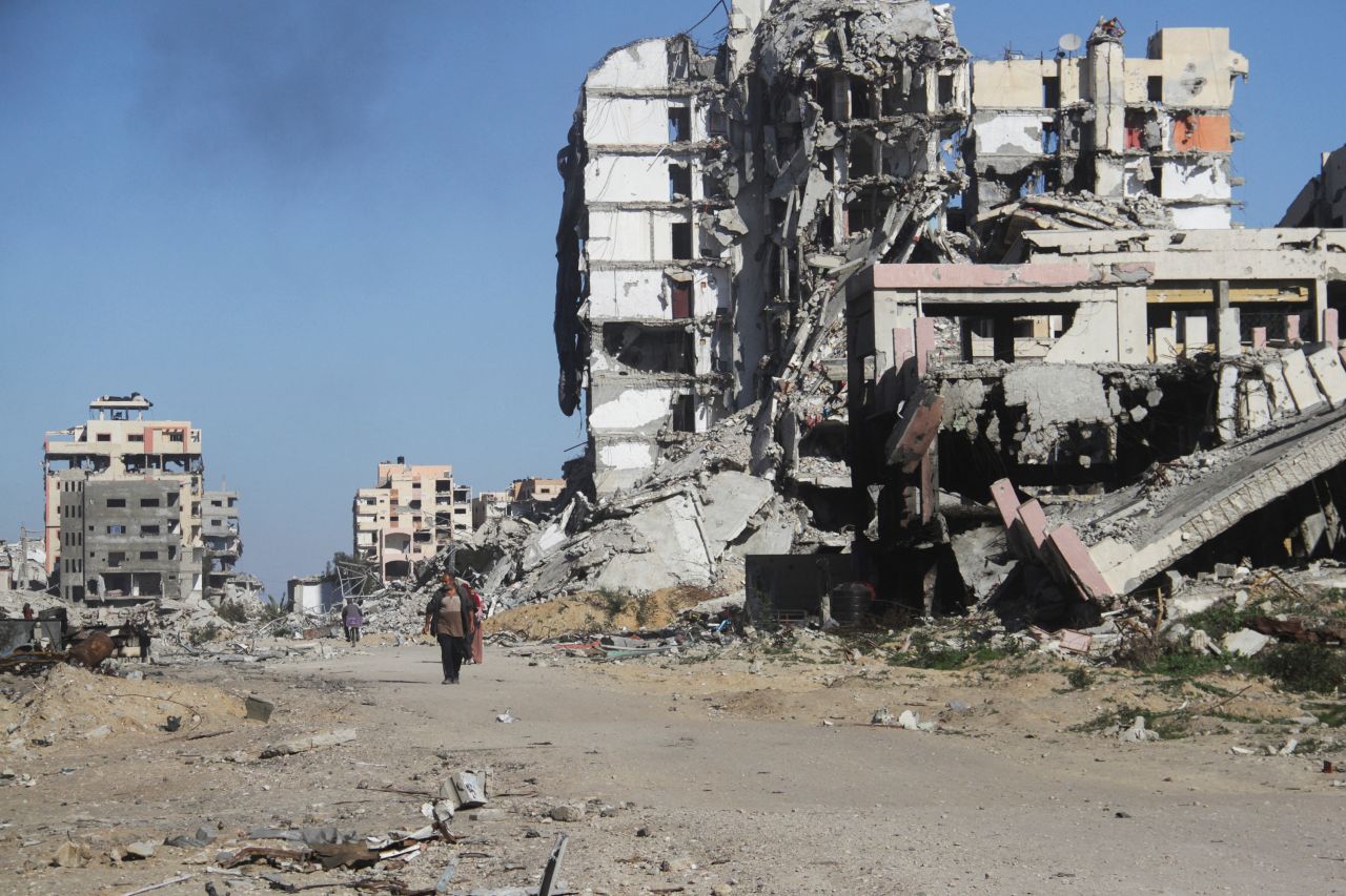 Palestinians walk past damaged buildings, before a ceasefire between Israel and Hamas takes effect, in Gaza City, January 19, 2025. REUTERS/Mahmoud Issa