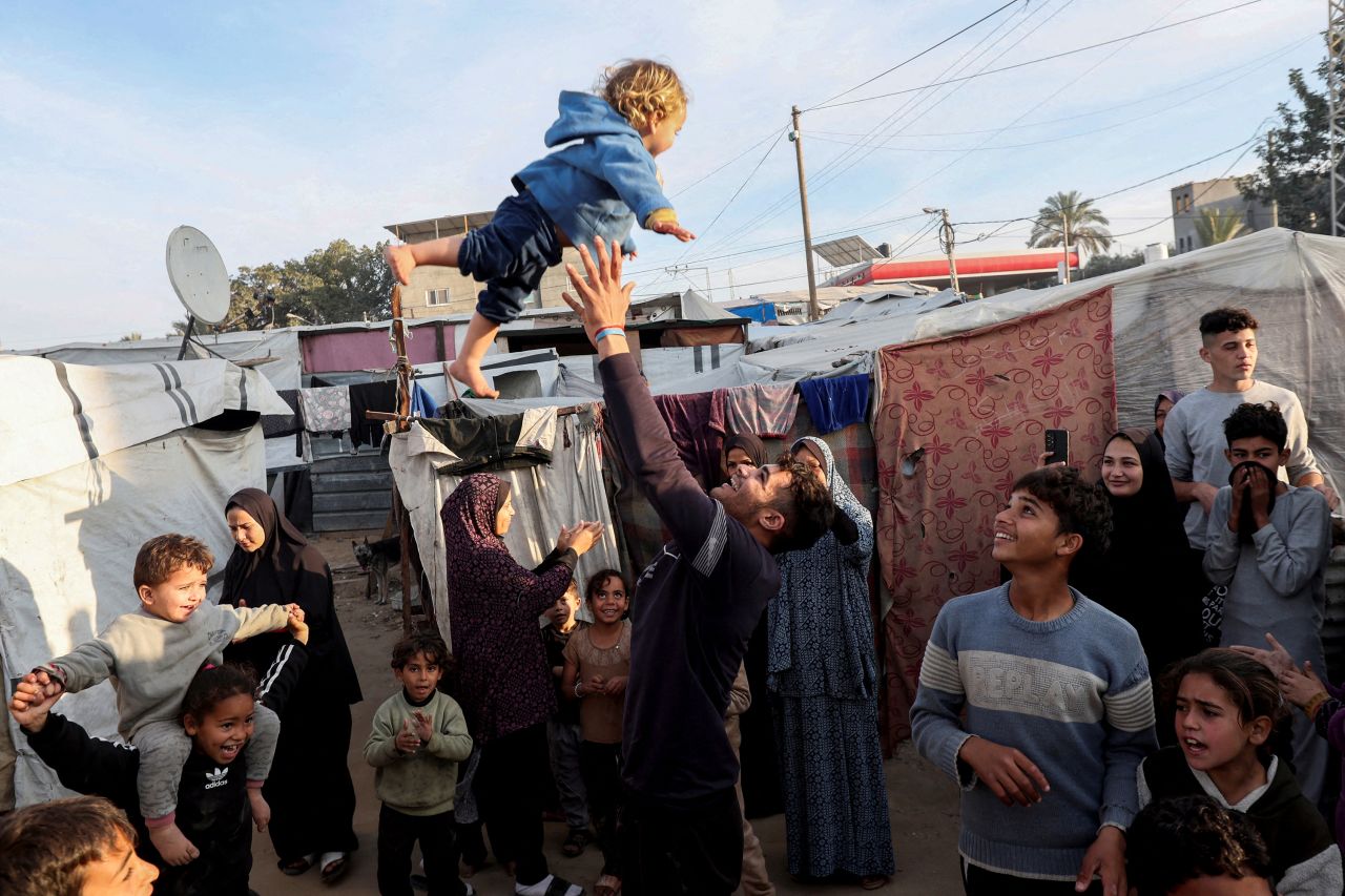 A man throws a child into the air as displaced Palestinians celebrate at a tent camp in Deir Al-Balah, Gaza, on Sunday.