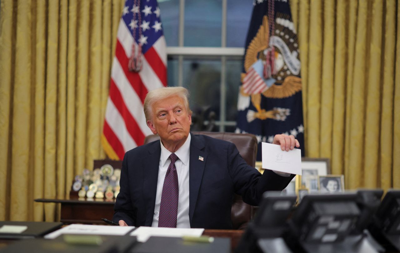 US President Donald Trump holds former United States President Joe Biden's letter as he signs executive orders in the Oval Office on Monday.