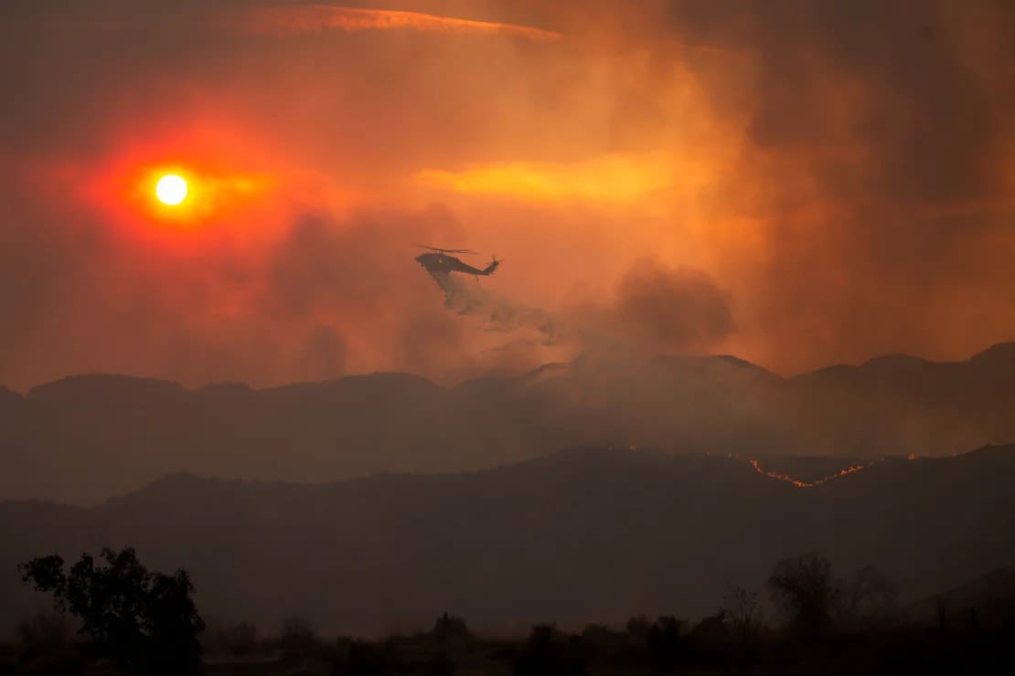 Un helicóptero arroja agua mientras los bomberos luchan contra el incendio Hughes cerca del lago Castaic el miércoles.