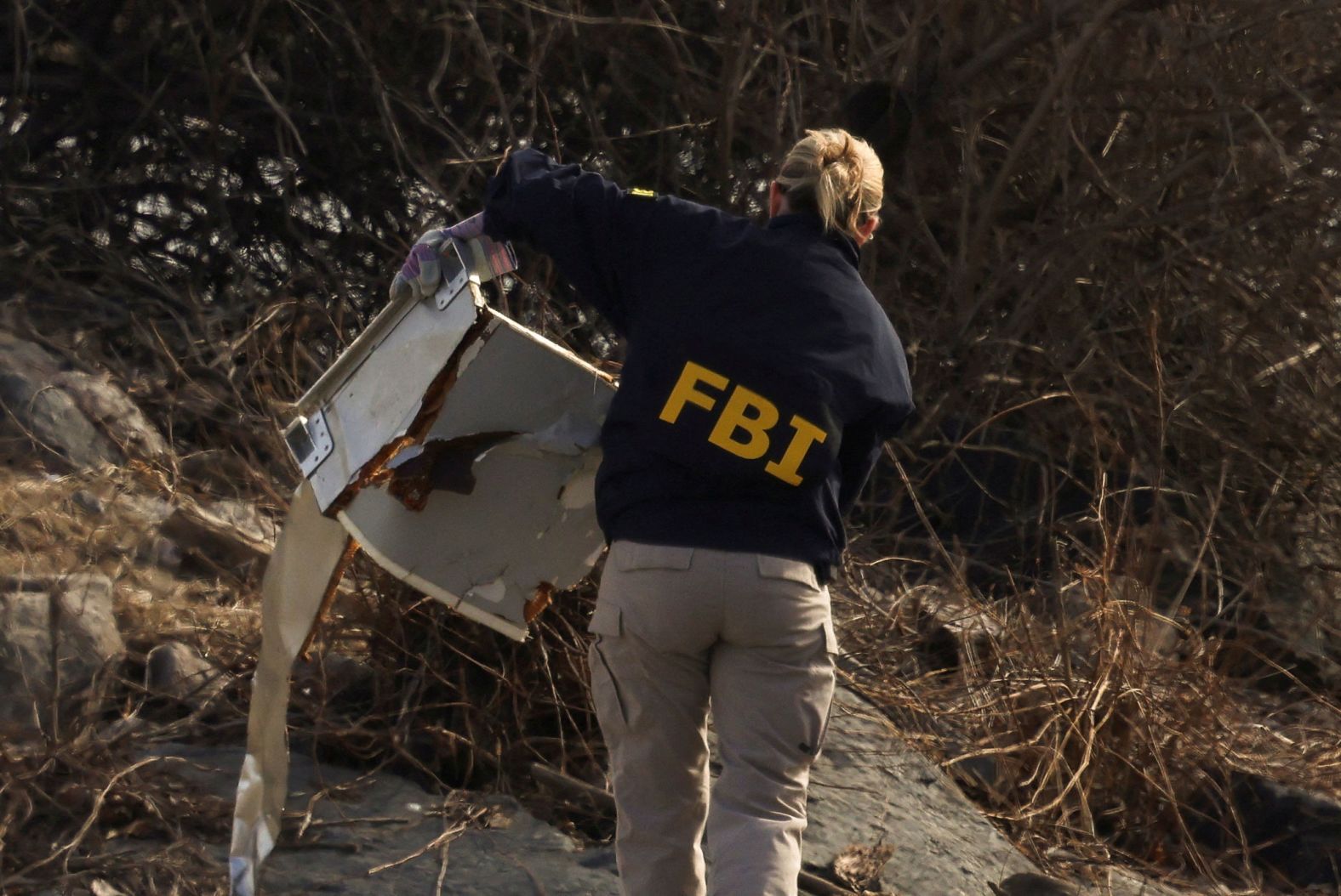 An FBI agent carries debris from the wreckage on Thursday, January 30.