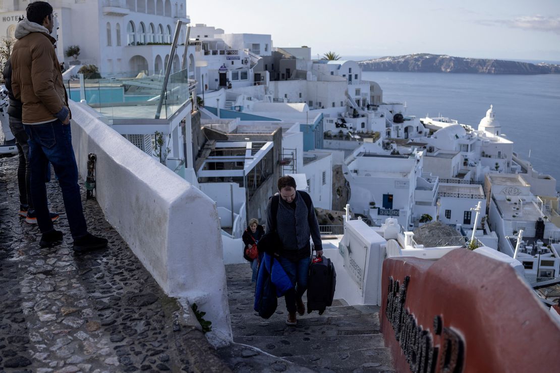 Tourists carry their luggage as they leave the village of Fira, following increased seismic activity on the island of Santorini, Greece, on Tuesday.