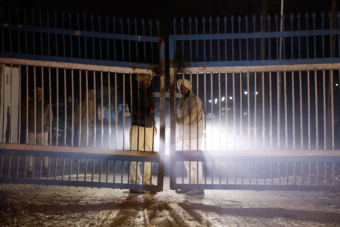 Police are being guarded by gates as vehicles transporting deported migrants depart from the airport in Amritsar, India on Wednesday.