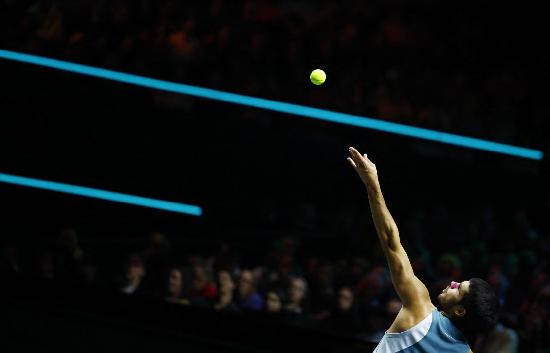 Alcaraz plays a serve against de Minaur.