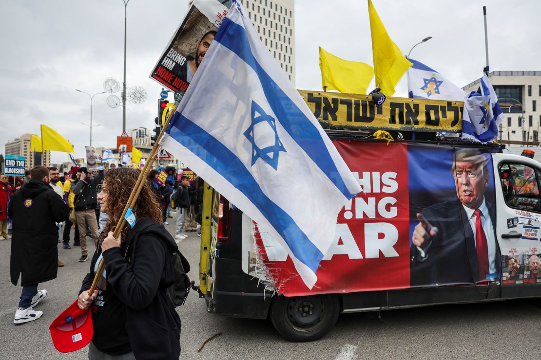 A woman carries an Israeli flag in Jerusalem next to a banner with an image of Trump, during a demonstration calling for the immediate return of hostages on February 11.
