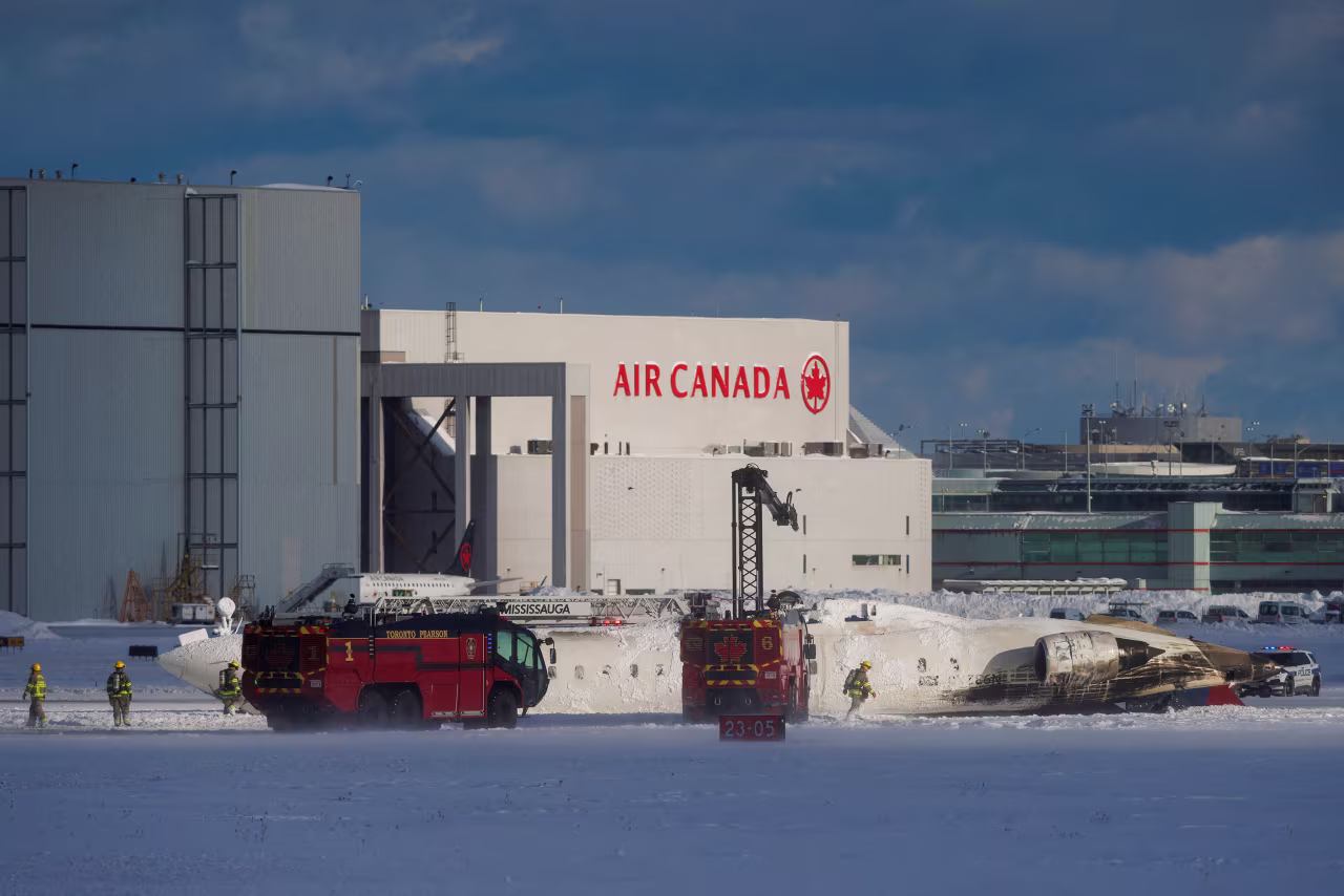 Emergency responders walk around the plane on a runway.