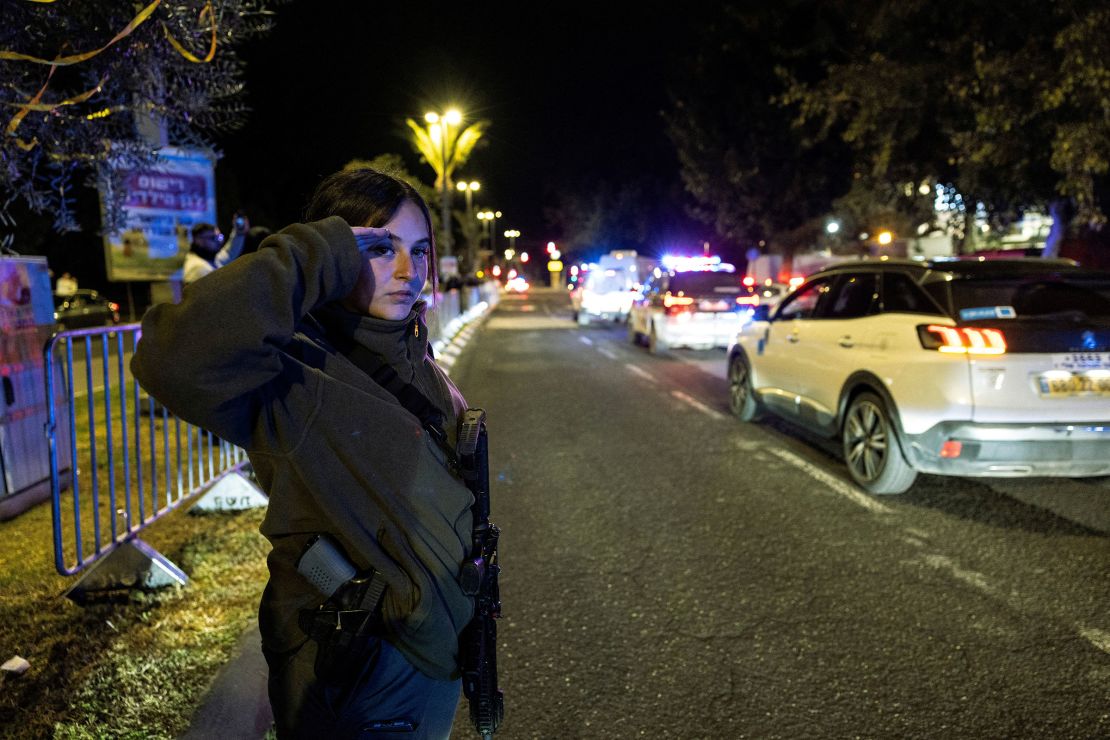 An Israeli border police officer salutes as a van carrying the body of Shiri Bibas arrives in Tel Aviv.