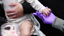 Sherry Andrews holds a 13-month-old's hand after giving the child its first MMR vaccine dose in Lubbock, Texas, on February 27.