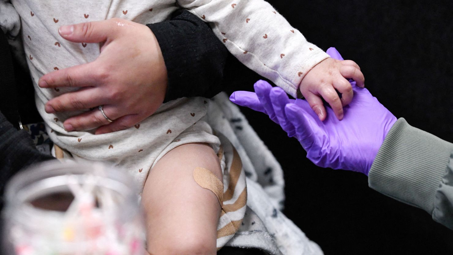 Sherry Andrews holds a 13-month-old's hand after giving the child its first MMR vaccine dose in Lubbock, Texas, on February 27.