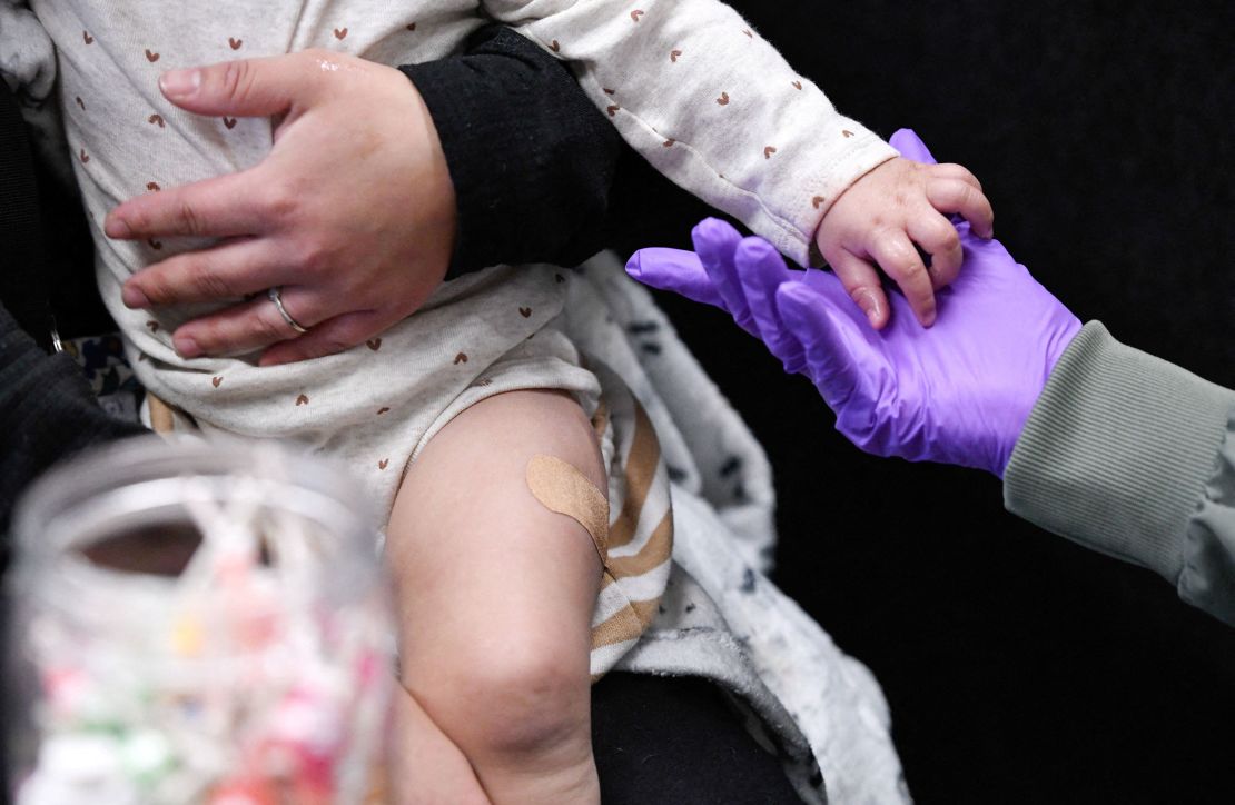 Sherry Andrews holds a 13-month-old hand last month after administering an MMR dose in Lubbock, Texas.