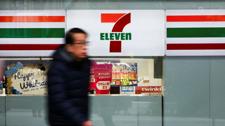 A man walks past the logo of 7-Eleven displayed at their convenience store in Tokyo, Japan March 6, 2025.