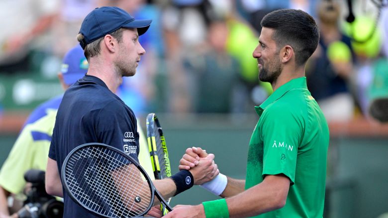 Novak Djokovic shakes hand with Botic van de Zandschlup after their match.