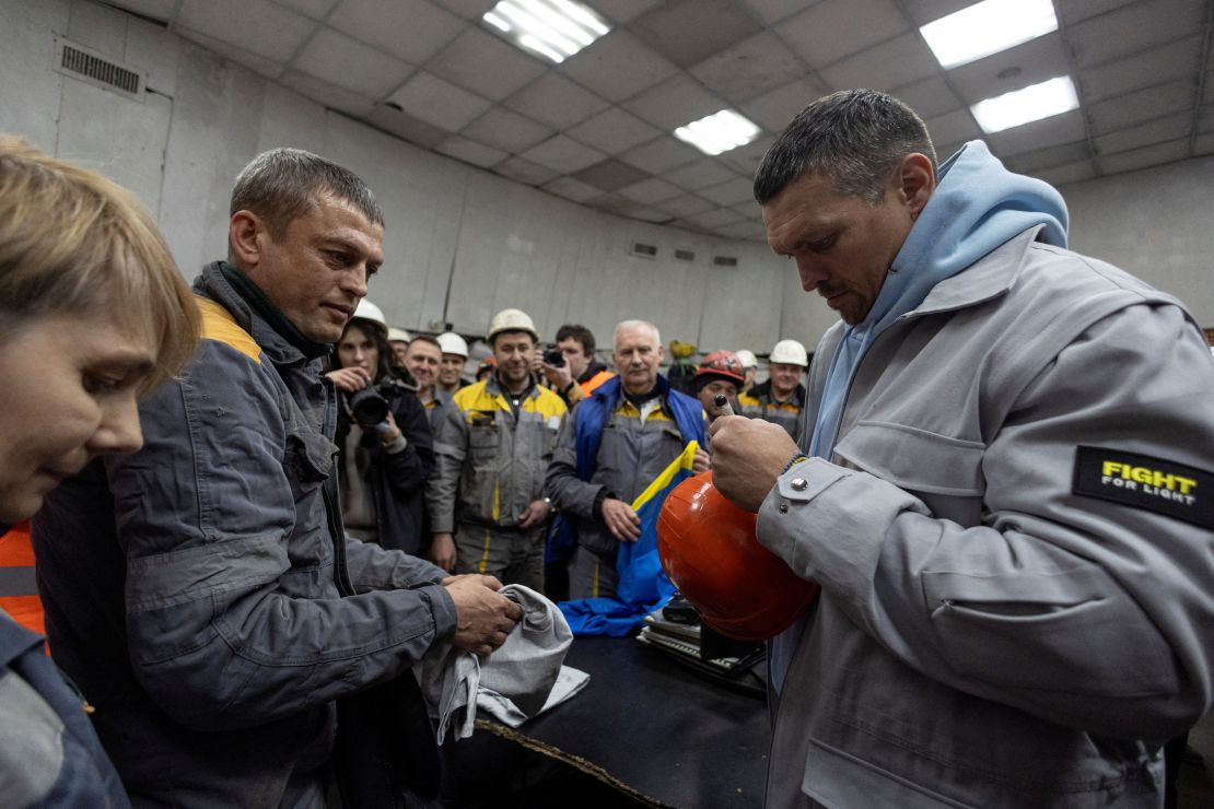 Oleksandr Usyk signs a protective helmet in March as he visits a thermal power plant in Ukraine that had been damaged by Russian missile strikes.