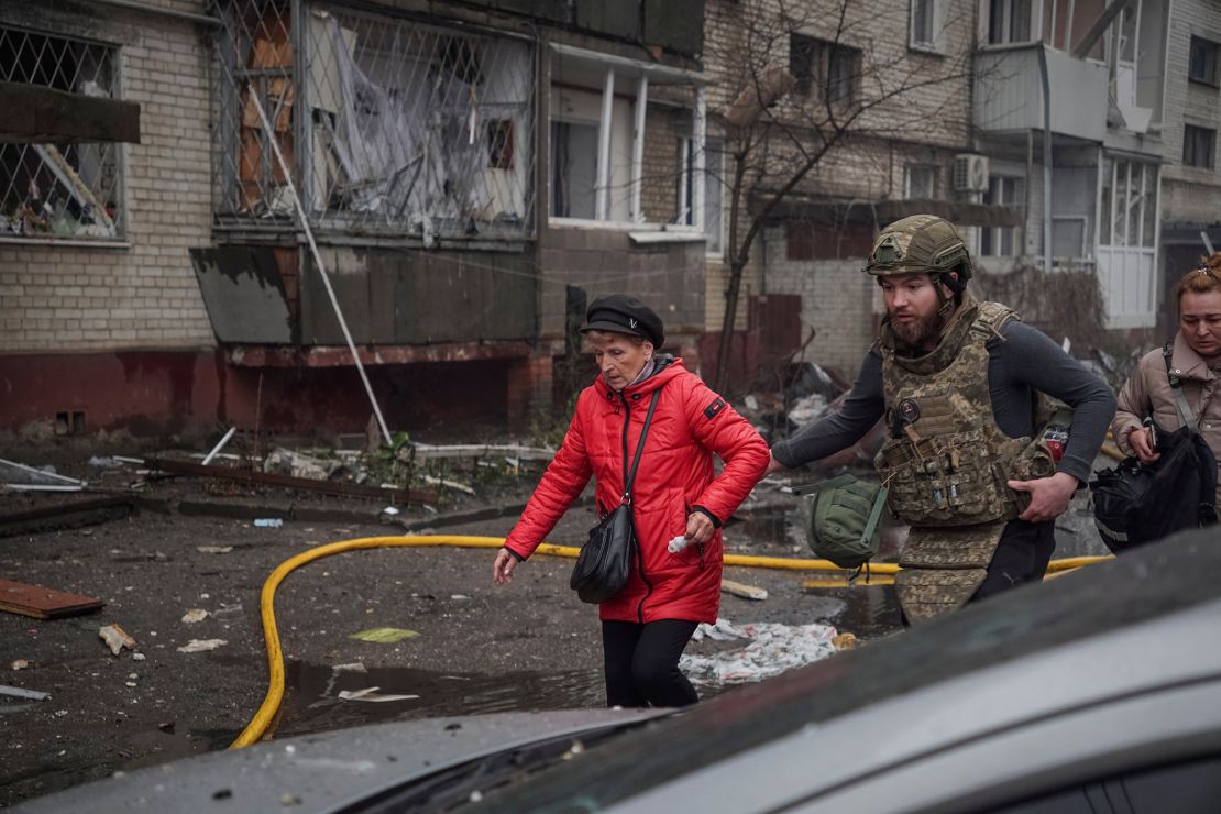 A Ukrainian serviceman evacuates a woman from an apartment building hit by a Russian missile strike, in Sumy, Ukraine, on Monday, March 24, 2025.