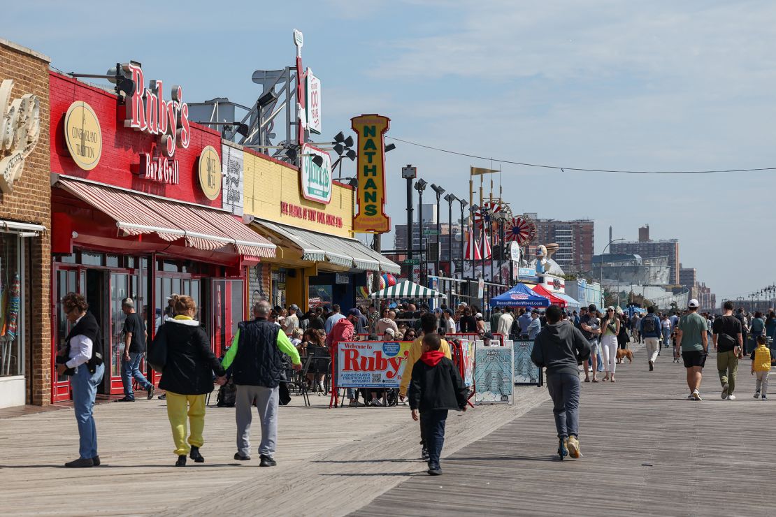 People walk down the boardwalk at Coney Island in March 2025.