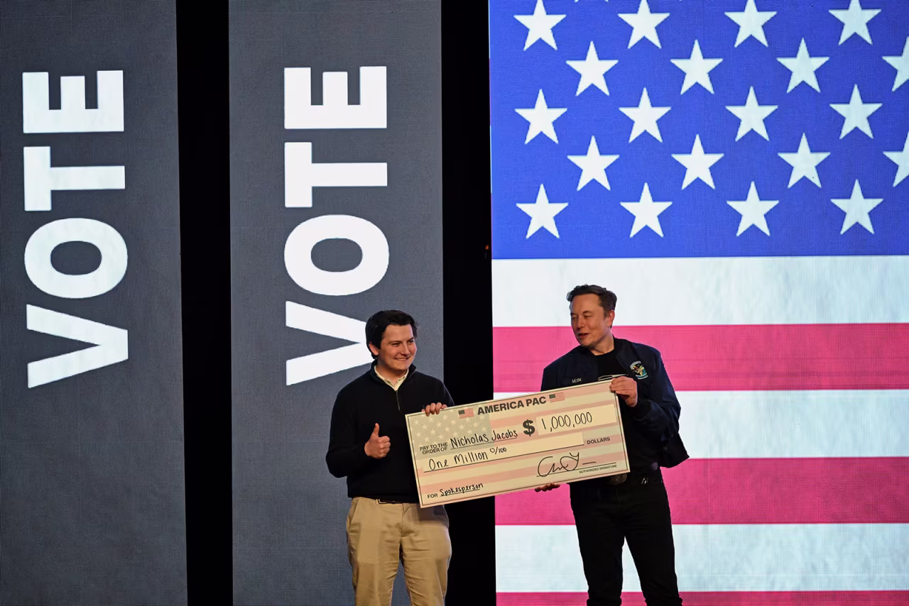 Elon Musk gives a check to an audience member during a rally in support of a conservative state Supreme Court candidate in Green Bay, Wisconsin, on Sunday.