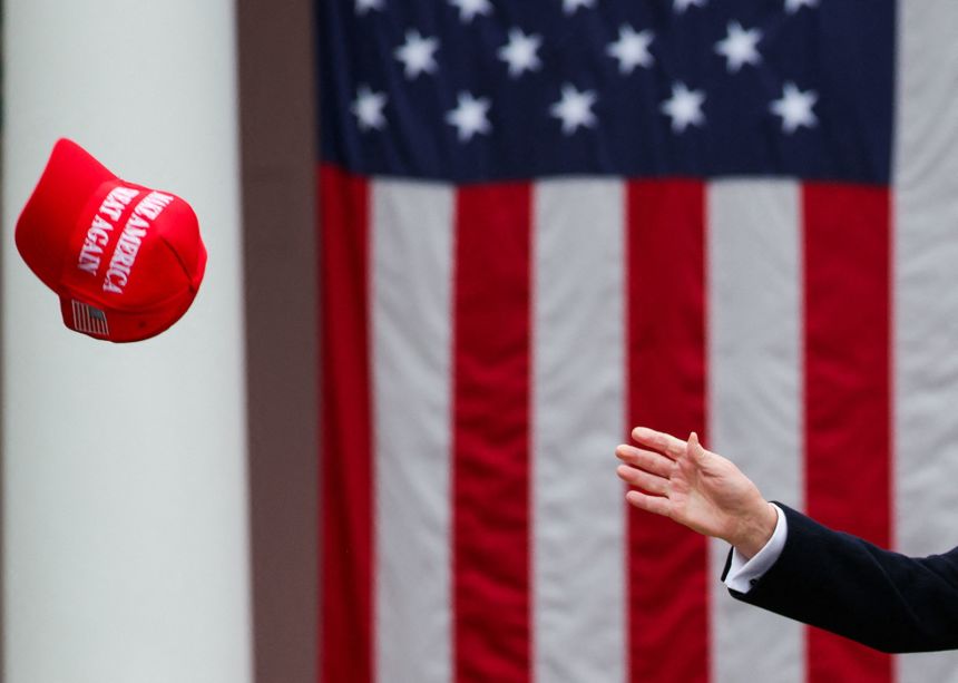 President Donald Trump tries to reach a MAGA hat on the day of his remarks on tariffs in the Rose Garden at the White House in Washington, DC, on April 2, 2025.