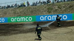 Safety officers extinguishing a trackside fire on the grass patch.