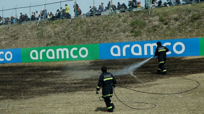 Safety officers extinguishing a trackside fire on the grass patch.