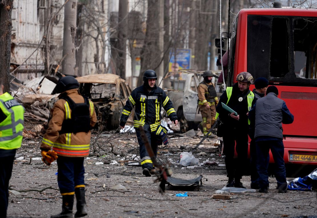 Rescuers work near a body of a victim and damaged vehicles at the site of a Russian missile strike in Sumy, Ukraine last month.