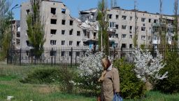 A woman walks past a war-damaged apartment building in Avdiivka, a Russian-occupied town in Ukraine's eastern Donetsk region, on April 20, 2025.