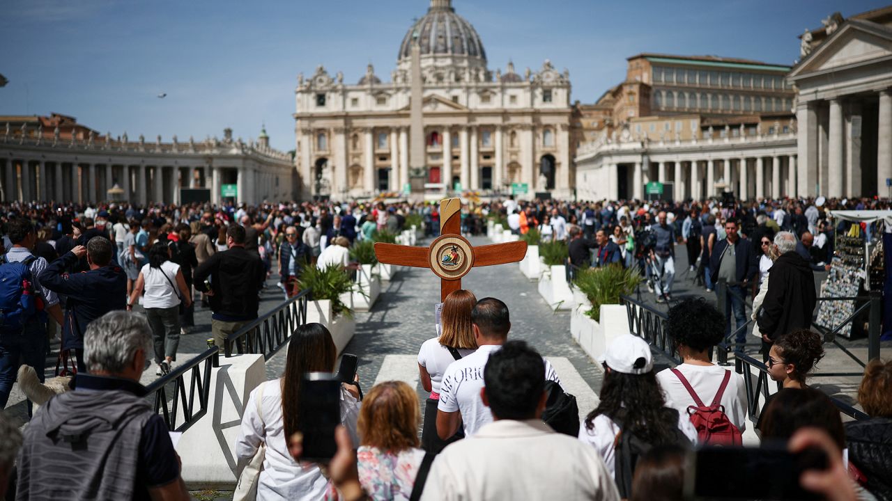 A pilgrim carries a cross near St Peter's square, after the death of Pope Francis was announced by the Vatican, as seen from Rome, Italy, April 21, 2025. REUTERS/Guglielmo Mangiapane